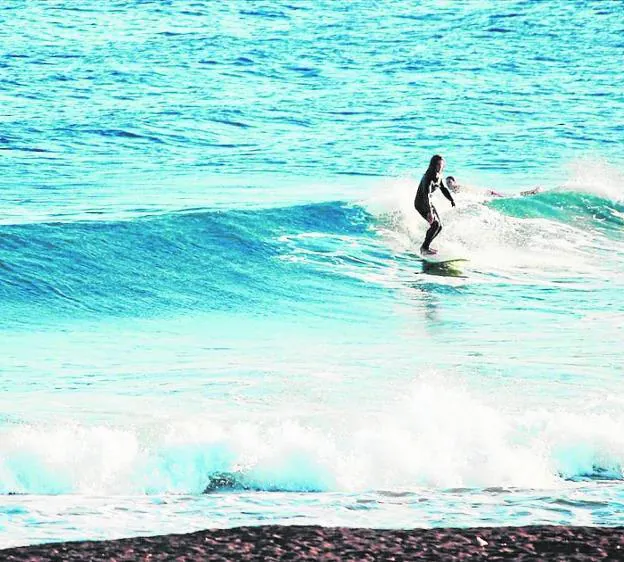Una mujer aprende a cabalgar las olas en la playa de Galúa. Shisha de sandía, al atardecer.