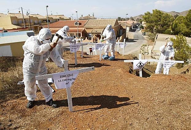 Vecinos ponen cruces sobre un depósito minero, ayer en Llano del Beal. 