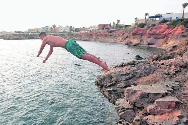Un bañista saltando al mar desde una roca de Cabo de Palos, en una práctica de riesgo que los socorristas tratan de frenar.