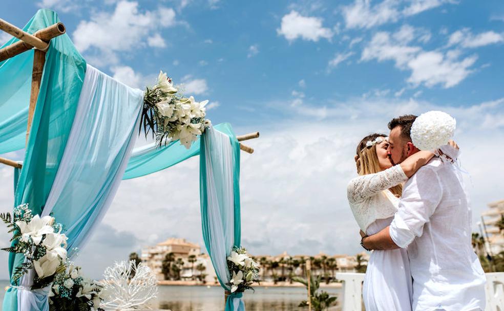 Alba y David se besan tras casarse a orillas del Mar Menor, en La Manga, con la urbanización El Pedruchillo al fondo.