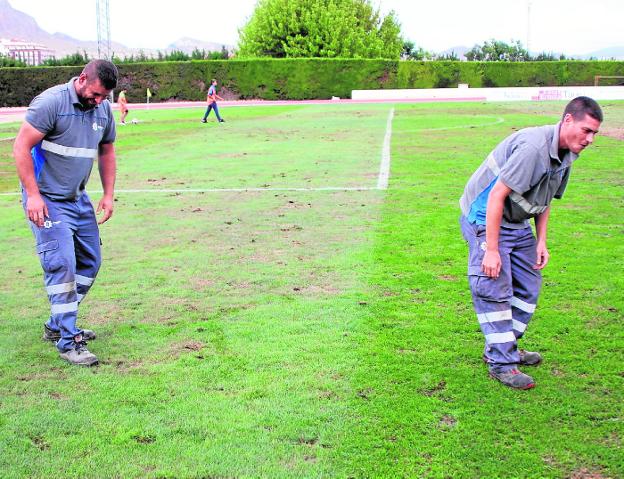 Operarios municipales intentan nivelar el césped en el descanso el domingo. 