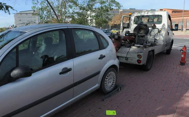 La grúa retira un vehículo aparcado sobre la acera.