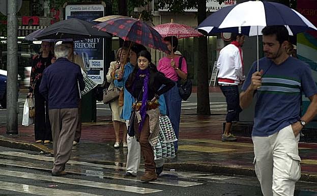 Peatones pasean bajo el paraguas en Murcia (archivo).