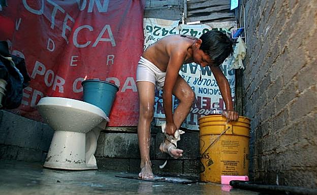 Un niño mexicano se lava con agua de un cubo antes de ir al colegio. 