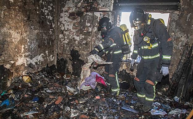 Bomberos trabajando en el apartamento donde se originó el fuego, lleno de basura.