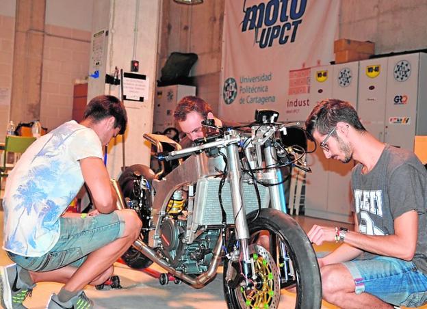 Tres estudiantes preparan la moto para la competición. 