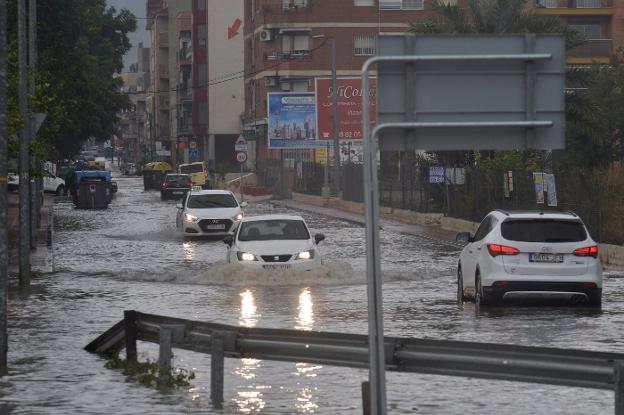 Los coches circulan por una calle anegada por las lluvias en la zona de Beniaján y Los Garres. 