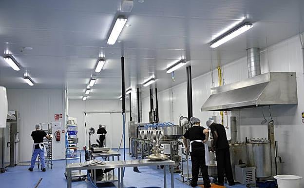 Imagen principal - Trabajadores de Foodtopía preparan las comidas que se sirven en los cuatro locales con que cuenta ya este proyecto. | Jesús Pagán, presidente de Foodtopía, muestra una bolsa con el residuo medio diario de una familia de 4 miembros. | Una trabajadora sirve una ración de lasaña vegetal para llevar.