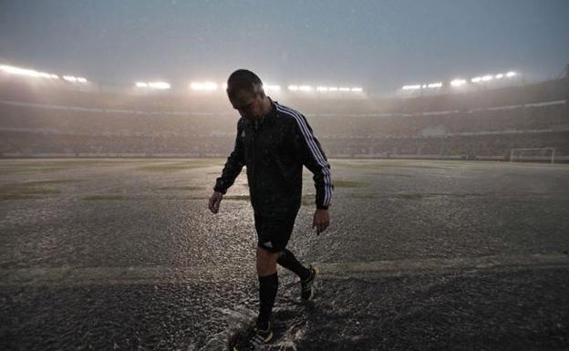 Un árbitro observa el terreno de juego con lluvia intensa en una imagen de archivo. 