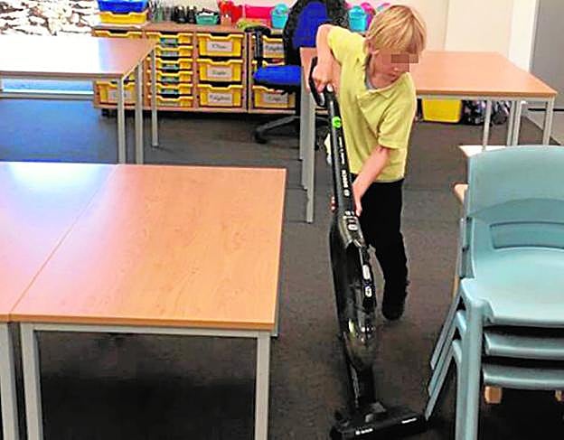Sammy, de seis años, pasa la aspiradora por una de las salas del colegio. 