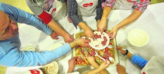 Varios niños, en plena elaboración de una pizza durante uno de los talleres de Minigourmet. 