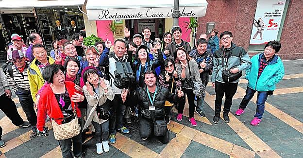 Uno de los dos grupos de taiwaneses que ayer visitaron Lorca posan con su guía, Pedro David Quiñonero (c), en la Corredera. 