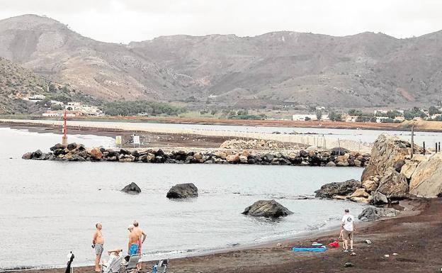 Varios bañistas junto a las obras de dragado de los estériles en la bahía de Portmán.