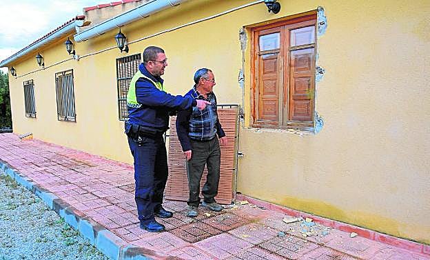 Un agente de la Policía Local de Ricote, Victoriano Garrido, junto a uno de los afectados, Matías Saorín, examinan los daños que los cacos dejaron en una de las ventanas. 