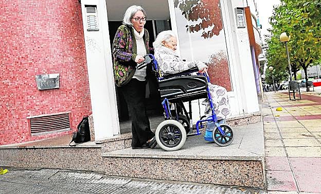 Carmen, en una imagen de diciembre de 2017, empujando la silla de ruedas de su madre, Ángeles, hasta la entrada del bloque para mostrar que no podía bajar a la acera para darse un paseo con ella. 