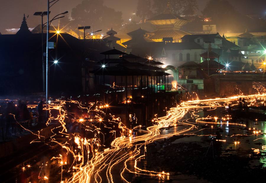 Los fieles hindúes nepalíes encienden lámparas de aceite y siembran siete tipos de semillas alrededor de las instalaciones del templo en nombre de los familiares difuntos.