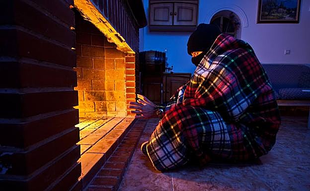 Una persona se calienta ante una chimenea.