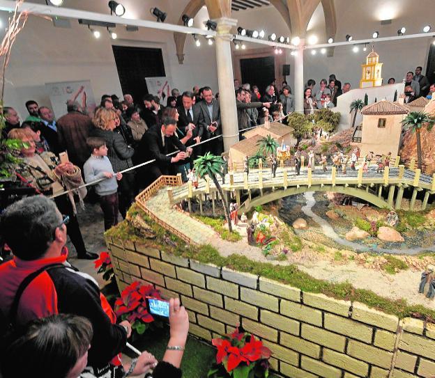 El patio porticado del Palacio de Guevara, ayer, repleto de público en la inauguración del belén municipal, presidido por la recreación del Puente de la Torta.