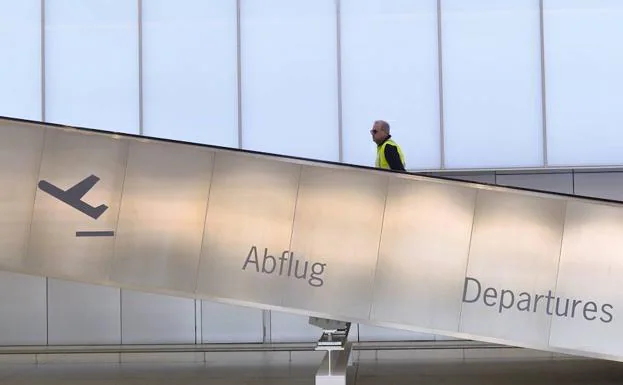 Un trabajador asciende por las escaleras mecánicas del aeropuerto.