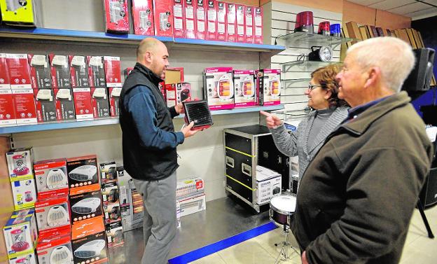 Un vendedor atiende a una pareja interesada en la compra de un calefactor. agm