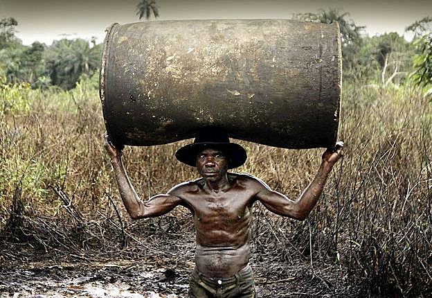 El nigeriano Ebiowei transporta un bidón vacío para llenarlo en una refinería ilegal cerca del río Nun.