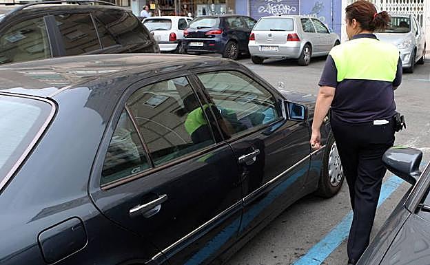 Una controladora de la ORA revisa el tique de un vehículo estacionado en Murcia.