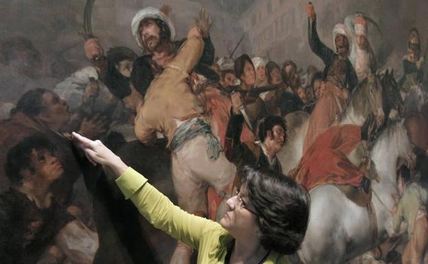 Una mujer señala un cuadro en el Museo del Prado. 