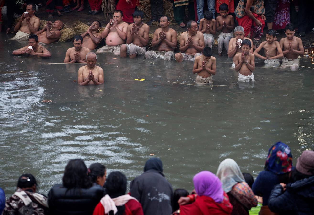 Devotos toman un baño sagrado en el río Hanumante durante el último día del Festival Madhav Narayan en Bhaktapur (Nepal). El Madhay Narayan se celebra durante un mes completo en el que se toman baños sagrados para lavar los pecados y se estudia el libro Swasthani. La veneración a la diosa Swasthani, una festividad que solo se conmemora en Nepal, es única en cada pueblo, con celebraciones y tradiciones diferentes.