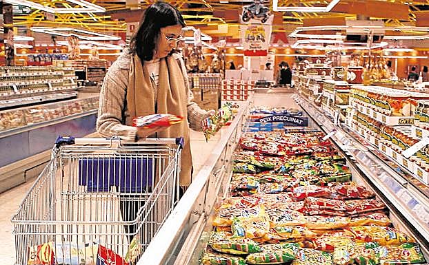 Una mujer compara productos en un supermercado.