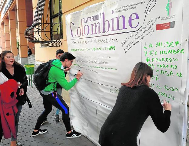 Varios jóvenes escriben sus titulares soñados para el futuro en el mural instalado por Colombine. 