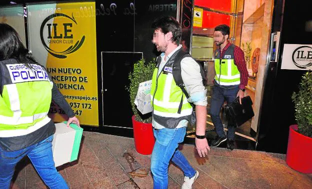 Investigadores del Cuerpo Nacional de Policía abandonando el centro, en la noche del martes, con cajas de documentación. 