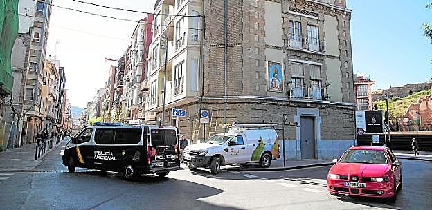 Un furgón de la Policía Nacional pasa junto a una unidad móvil de Iberdrola, que ayer anuló un enganche ilegal a las viviendas ocupadas en la calle San Vicente. 