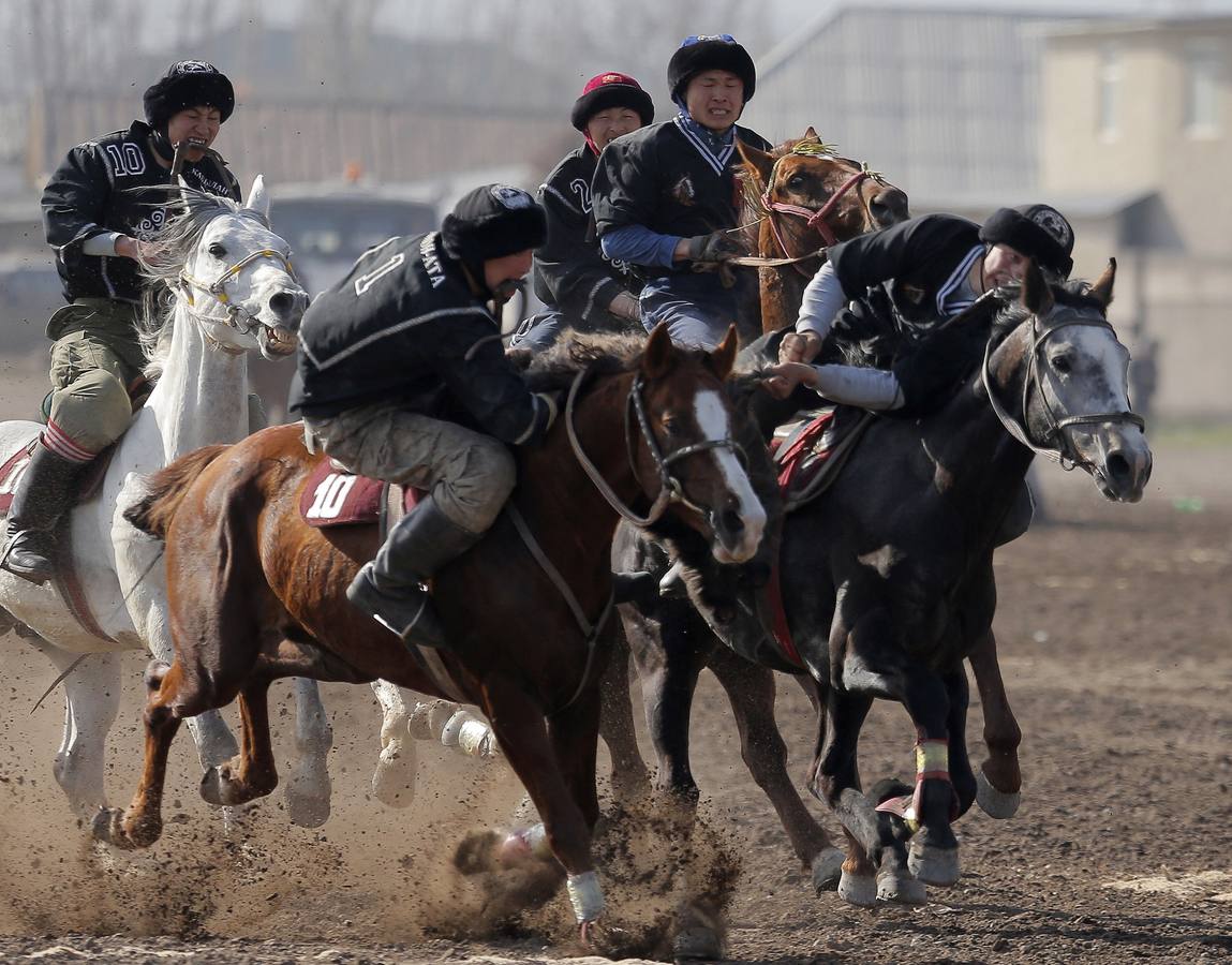 Varios jinetes participan en la competición tradicional kirguizistana llamada 'Kok-Boru', o arrastre de la cabra, con motivo de las celebraciones del Año Nuevo en el calendario solar persa, en Biskek (Kirguizistán). En el Kok-Boru los jugadores deben agarrar el cuerpo de una cabra desde el suelo mientras montan a caballo e intentar anotar un tanto al dejarlo sobre la portería del contrario.