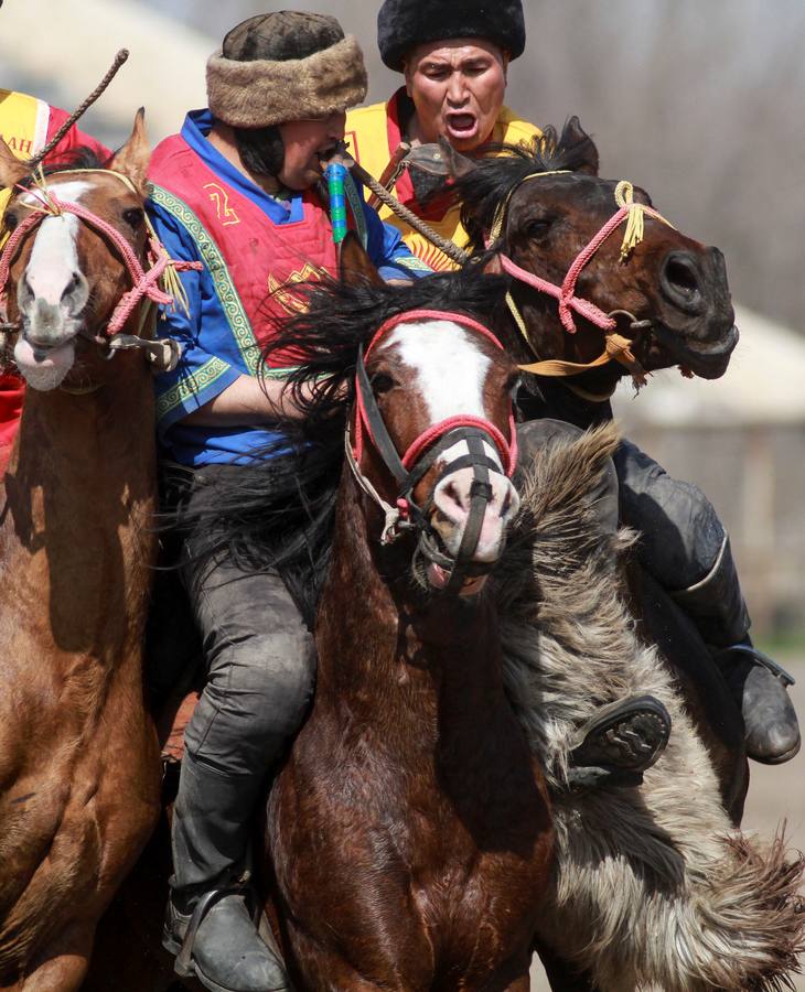 Varios jinetes participan en la competición tradicional kirguizistana llamada 'Kok-Boru', o arrastre de la cabra, con motivo de las celebraciones del Año Nuevo en el calendario solar persa, en Biskek (Kirguizistán). En el Kok-Boru los jugadores deben agarrar el cuerpo de una cabra desde el suelo mientras montan a caballo e intentar anotar un tanto al dejarlo sobre la portería del contrario.