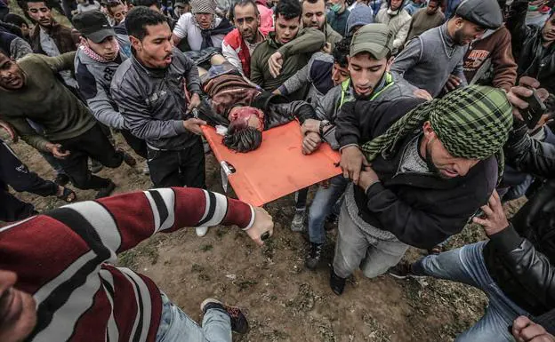 Manifestantes palestinos llevan el cuerpo de 17 años identificado como Adham Omara después de que un francotirador israelí lo disparara.