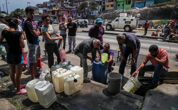 Ciudadanos recogen agua de un desagüe en Caracas.