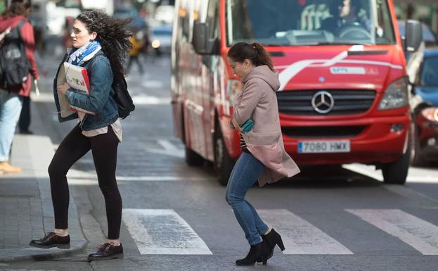 Una mujer se intenta refugiar del viento en Murcia.