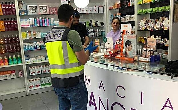 Un agente de la Policía Nacional, en una de las farmacias atracadas este martes en Murcia.