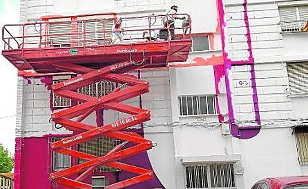 Los artistas, subidos a un andamio para pintar la fachada de uno de los edificios del barrio de La Paz. 