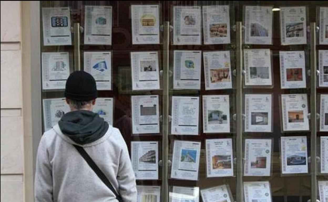 Un cliente observa ofertas de pisos en una inmobiliaria.