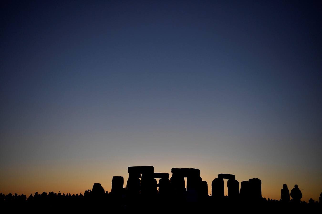 Varios entusiastas reciben el amanecer mientras participan en las celebraciones por el solsticio de verano en Stonehenge, en Wiltshire (Reino Unido). Este festival atrae anualmente a cientos de personas para celebrar el llegada del día más largo en el hemisferio norte.