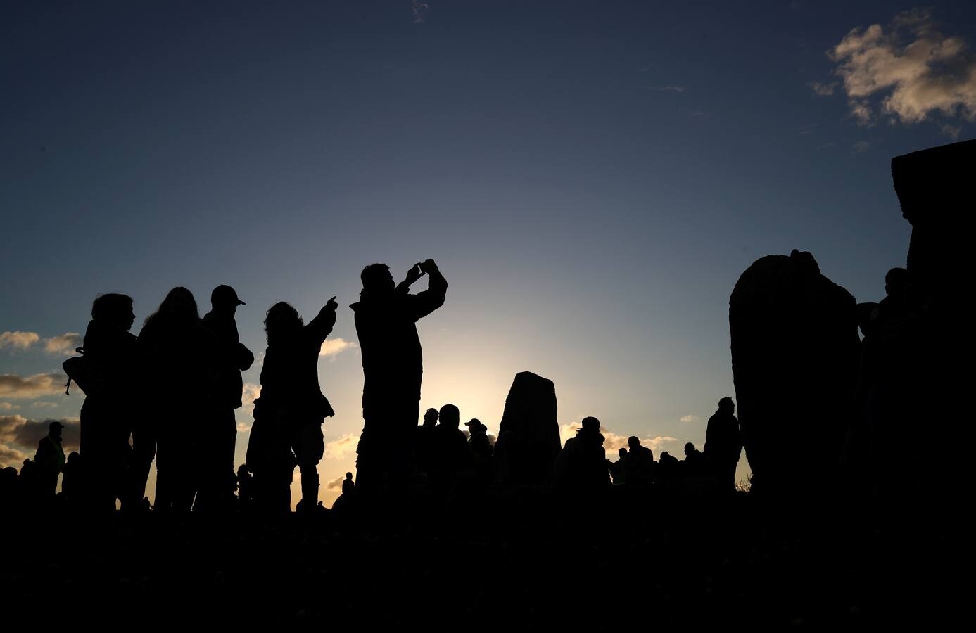 Varios entusiastas reciben el amanecer mientras participan en las celebraciones por el solsticio de verano en Stonehenge, en Wiltshire (Reino Unido). Este festival atrae anualmente a cientos de personas para celebrar el llegada del día más largo en el hemisferio norte.