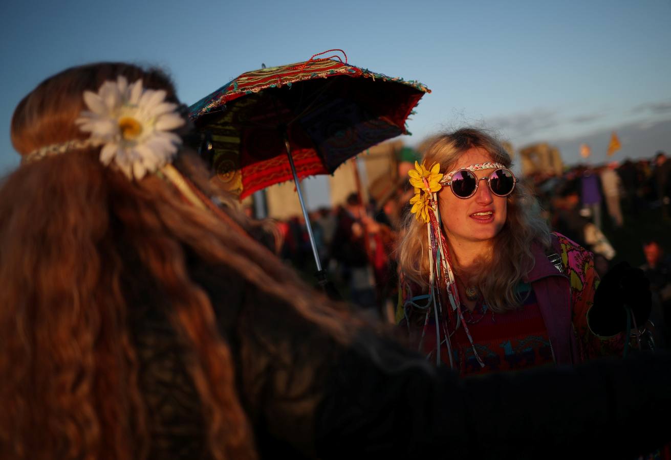 Varios entusiastas reciben el amanecer mientras participan en las celebraciones por el solsticio de verano en Stonehenge, en Wiltshire (Reino Unido). Este festival atrae anualmente a cientos de personas para celebrar el llegada del día más largo en el hemisferio norte.