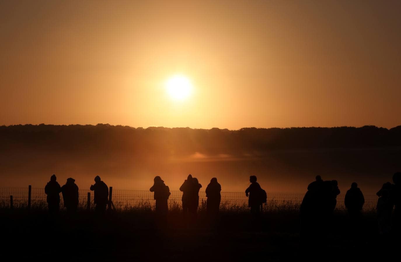 Varios entusiastas reciben el amanecer mientras participan en las celebraciones por el solsticio de verano en Stonehenge, en Wiltshire (Reino Unido). Este festival atrae anualmente a cientos de personas para celebrar el llegada del día más largo en el hemisferio norte.