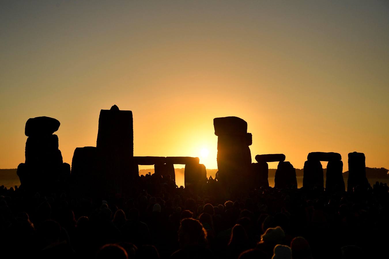 Varios entusiastas reciben el amanecer mientras participan en las celebraciones por el solsticio de verano en Stonehenge, en Wiltshire (Reino Unido). Este festival atrae anualmente a cientos de personas para celebrar el llegada del día más largo en el hemisferio norte.