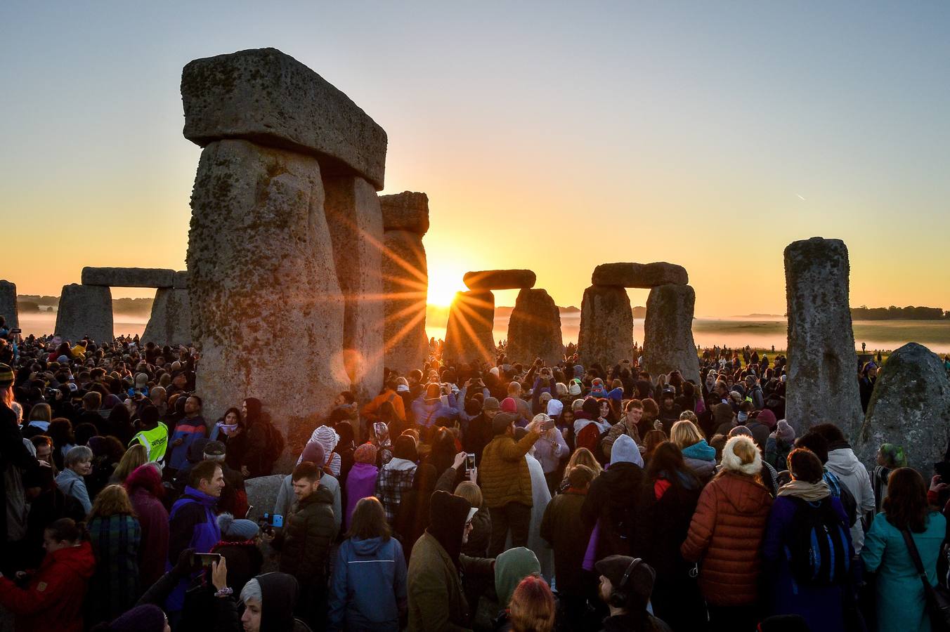 Varios entusiastas reciben el amanecer mientras participan en las celebraciones por el solsticio de verano en Stonehenge, en Wiltshire (Reino Unido). Este festival atrae anualmente a cientos de personas para celebrar el llegada del día más largo en el hemisferio norte.