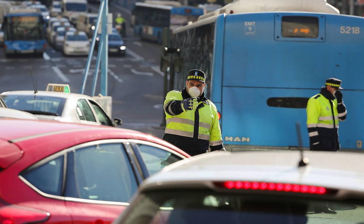 Dos policías dirigen el tráfico en Madrid ataviados con mascarillas.