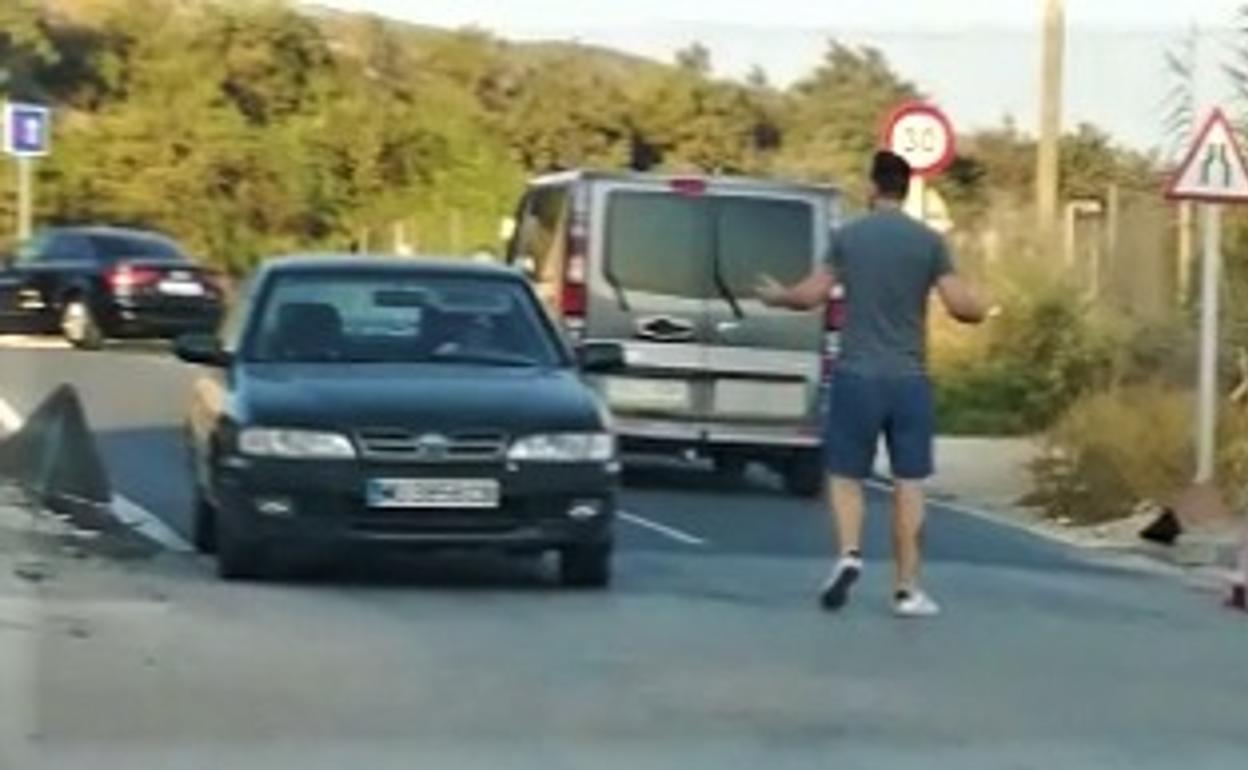 El joven, en mitad de la carretera, increpa a un conductor. 