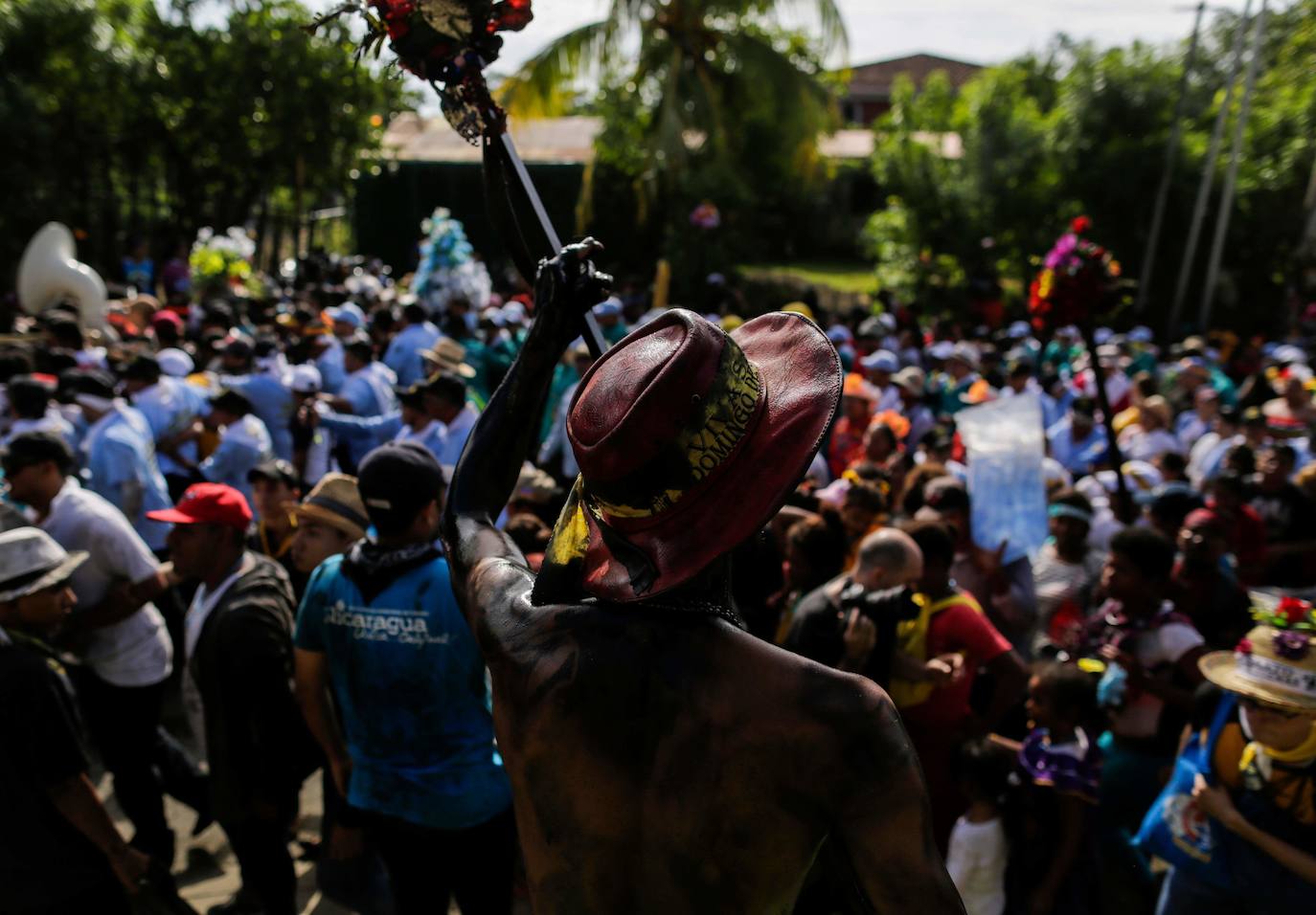 Varias personas llevan el cuerpo cubierto con aceite para cumplir con la tradición de «Los Diablitos Negros» durante una procesión en la que fieles católicos transportan la imagen de Santo Domingo de Guzmán, en Managua (Nicaragua). Como es tradición, la música pone el tono festivo y los creyentes bailan a la vez que avanzan hacia el norte de Managua, alrededor de la imagen, que es zangoloteada por los cargadores, como símbolo de alegría.