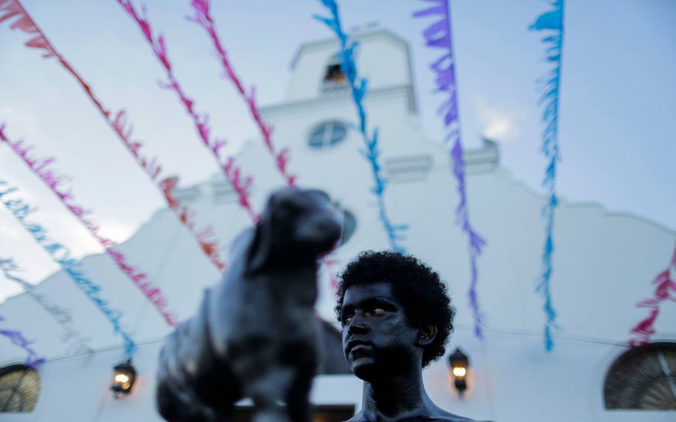 Varias personas llevan el cuerpo cubierto con aceite para cumplir con la tradición de «Los Diablitos Negros» durante una procesión en la que fieles católicos transportan la imagen de Santo Domingo de Guzmán, en Managua (Nicaragua). Como es tradición, la música pone el tono festivo y los creyentes bailan a la vez que avanzan hacia el norte de Managua, alrededor de la imagen, que es zangoloteada por los cargadores, como símbolo de alegría.